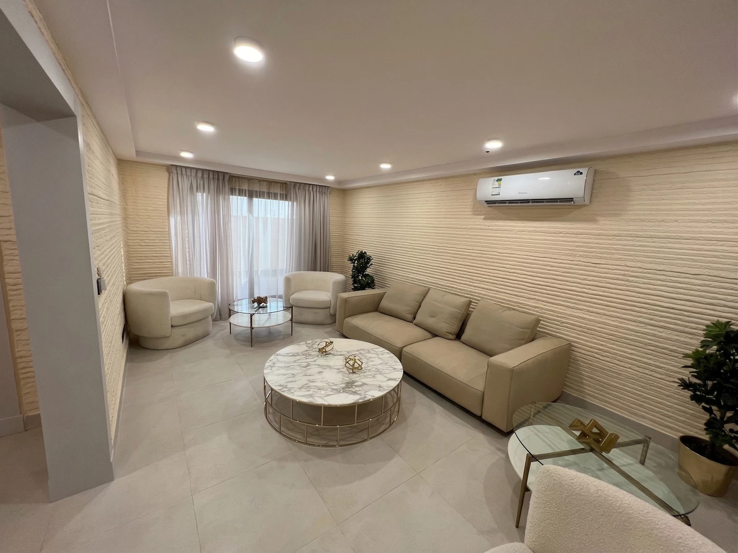 View of a luxury lounge with couches, coffee tables and cream coloured 3d printed concrete walls