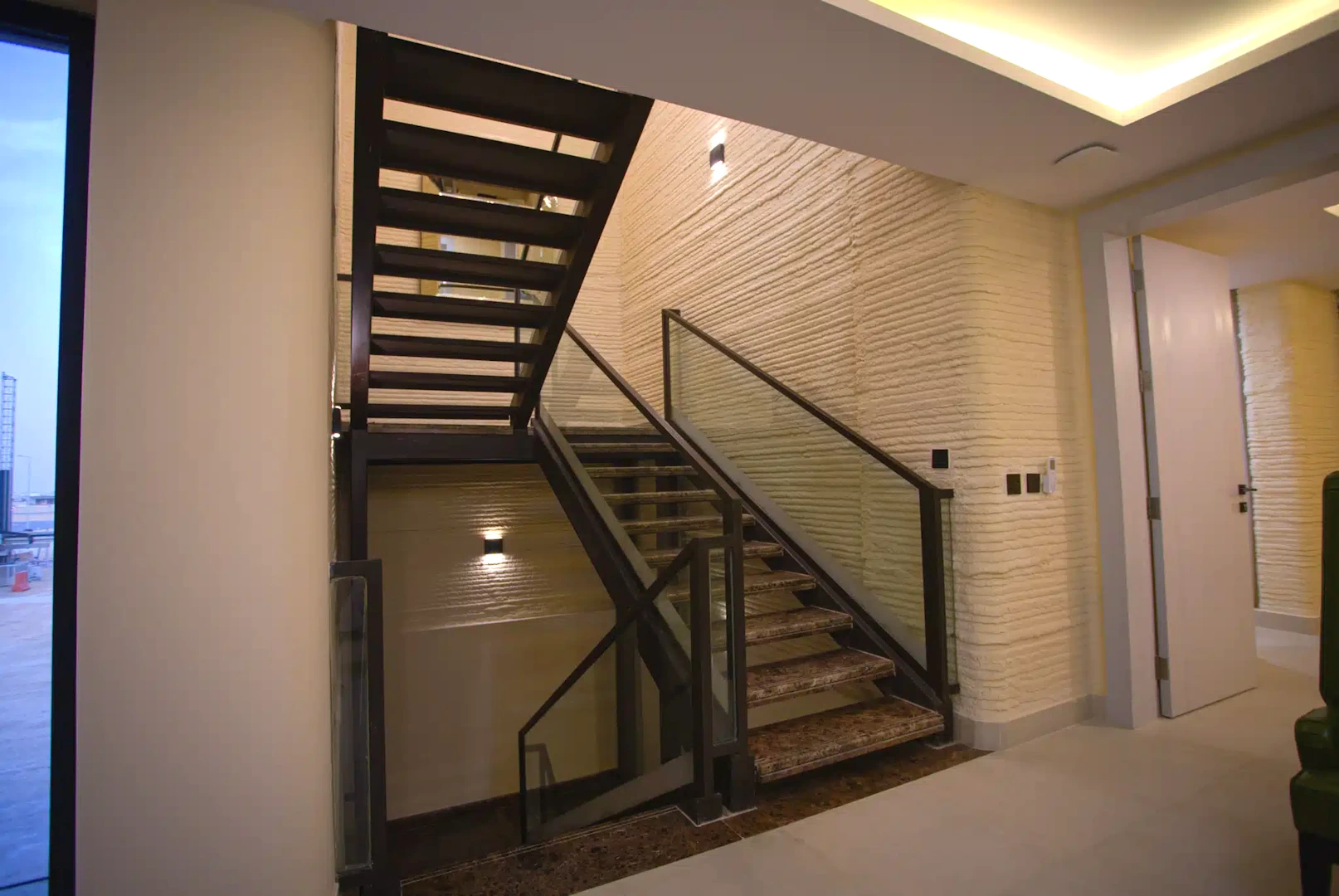 View of granite and metal stairway with cream coloured 3d printed concrete walls
