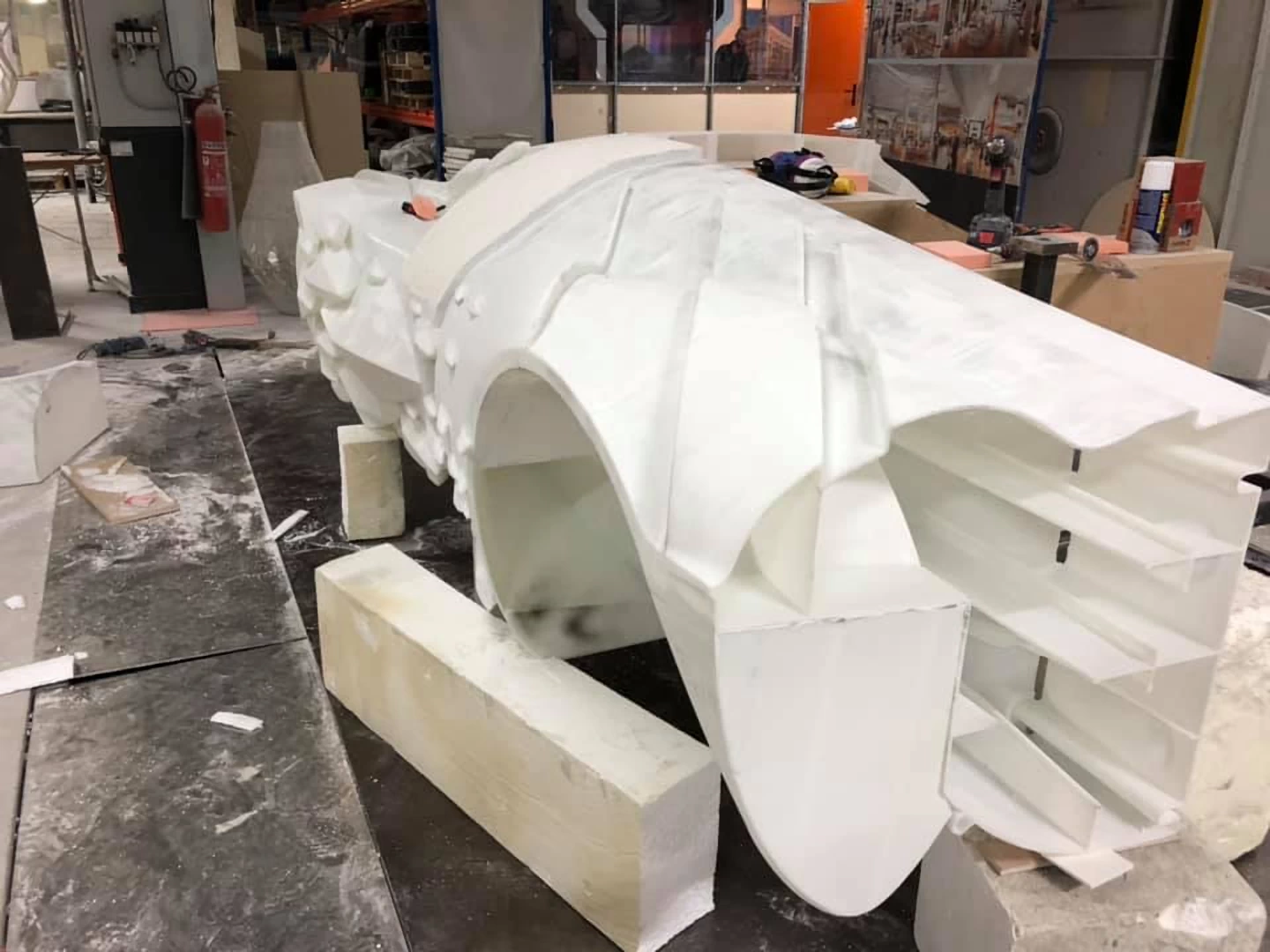 Rear left view of a white futuristic super car 3d printed in resin during assembly in a workshop