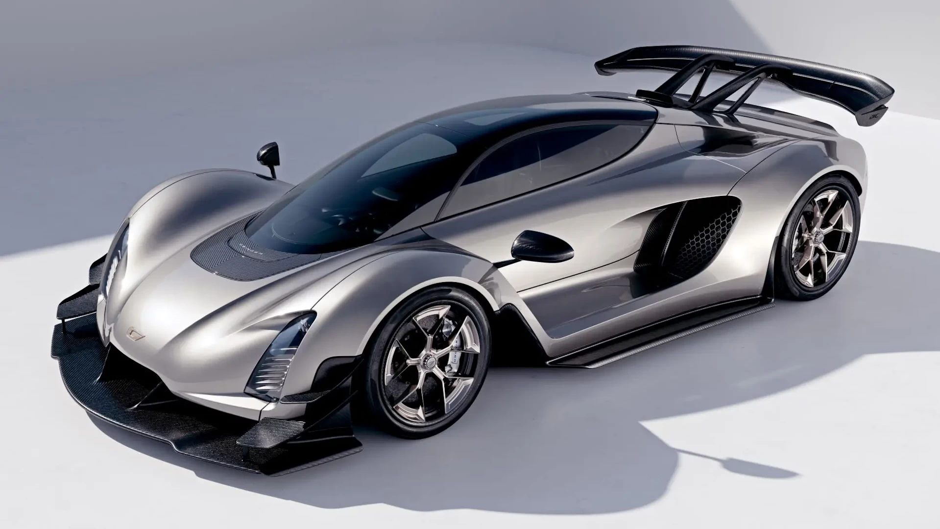 Front left view of a sleek silver 3d printed supercar against a white background