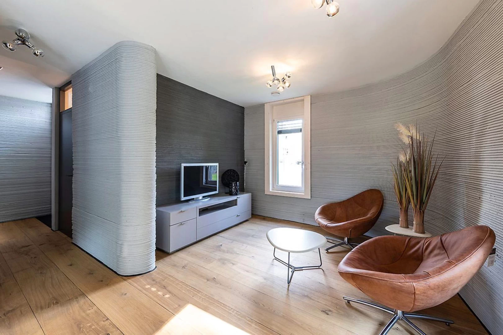 View of furnished lounge inside grey 3d printed concrete house