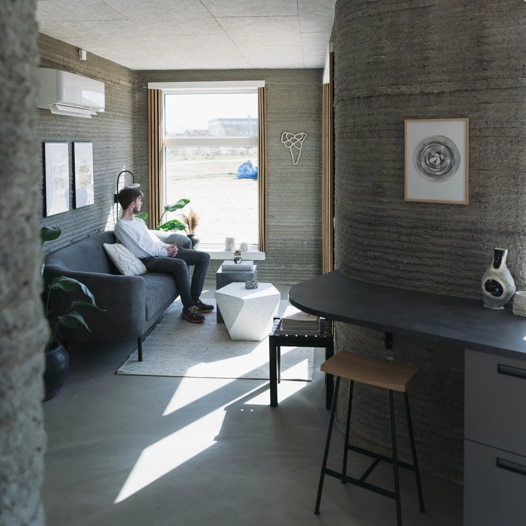 View of furnished lounge inside grey 3d printed concrete house