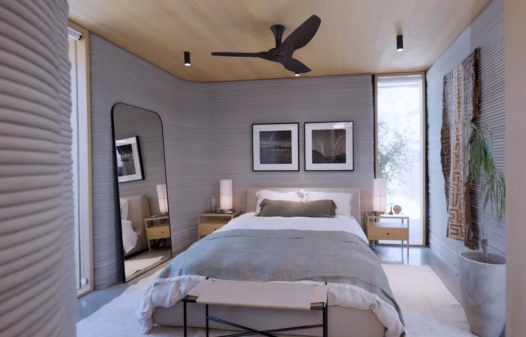 View of furnished bedroom inside grey 3d printed concrete house with wooden ceiling