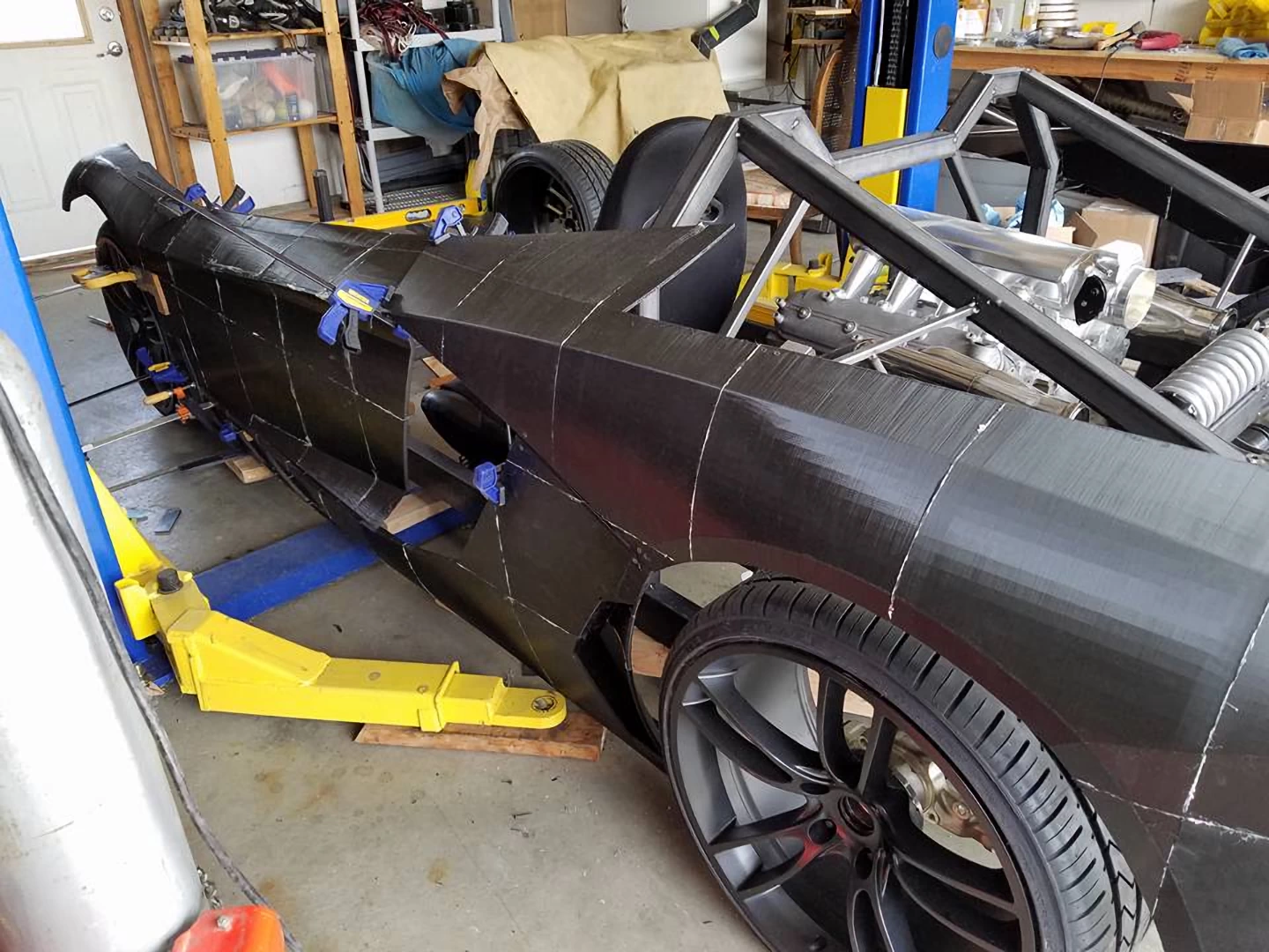 Left view of a black 3d printed plastic lamborghini aventador during assembly inside a garage