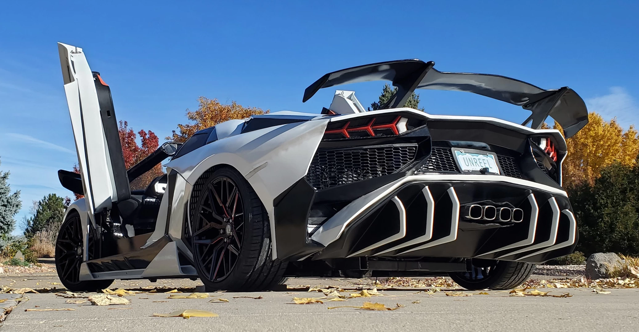 Rear left view of a white 3d printed plastic lamborghini aventador on a driveway