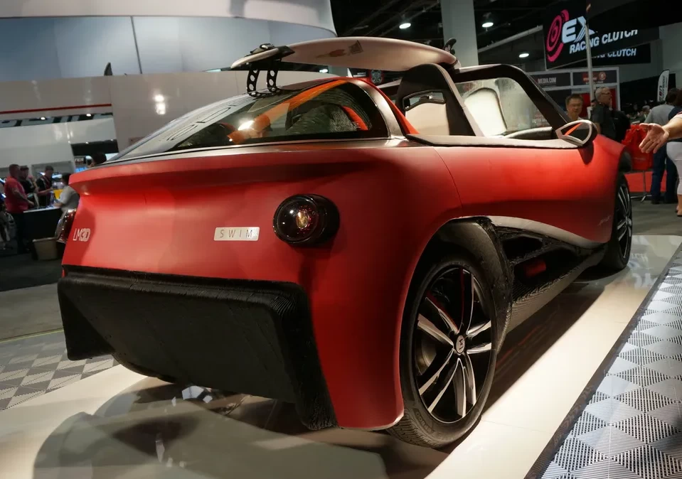 Back right view of a red 3d printed plastic beach buggy at a car show