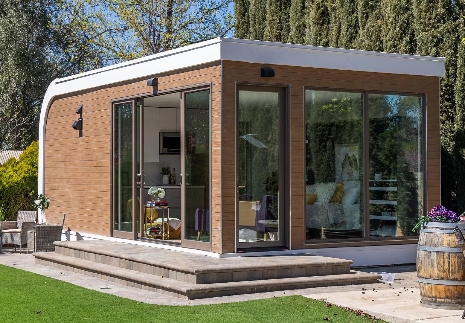 Corner view of white 3d printed resin house with wooden cladding, glass doors and a green lawn