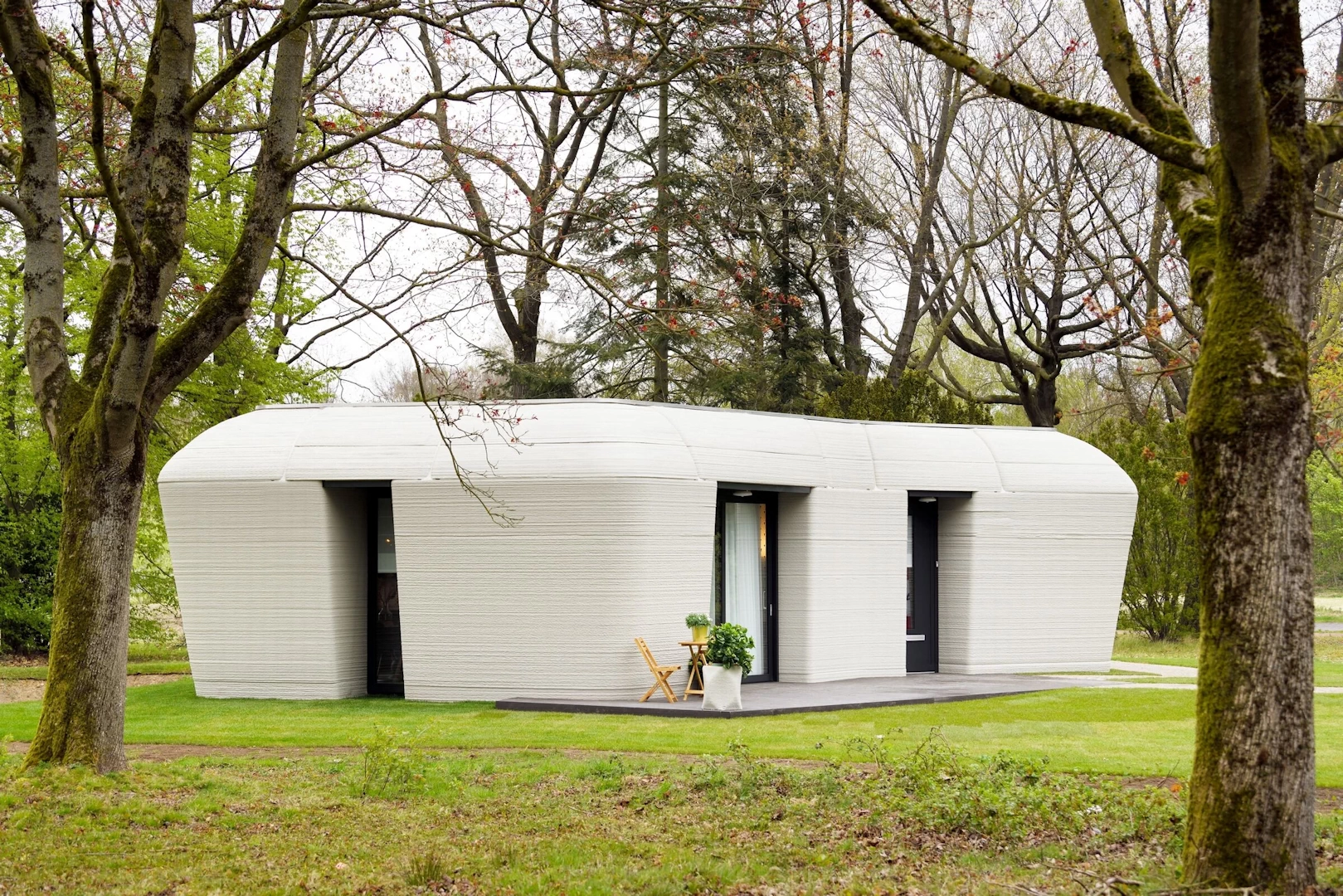 Corner view of white 3d printed concrete house with garden