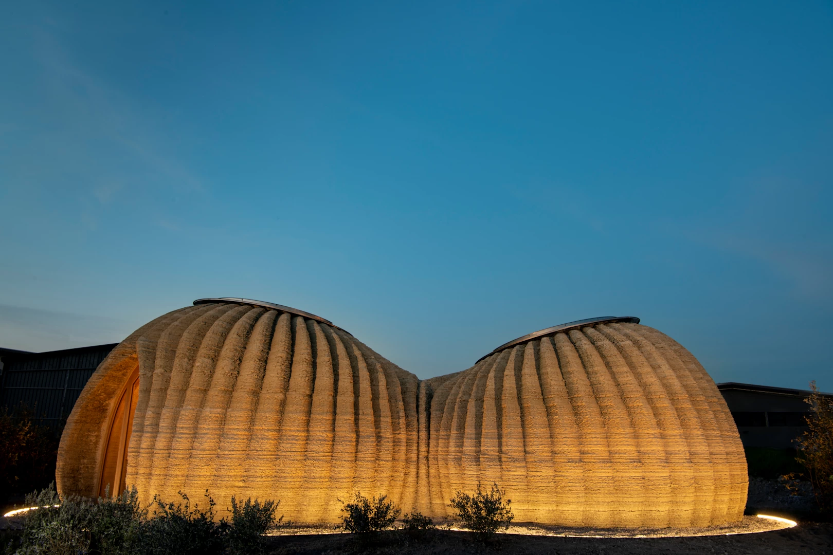 Side view of round brown 3d printed clay huts with textured walls