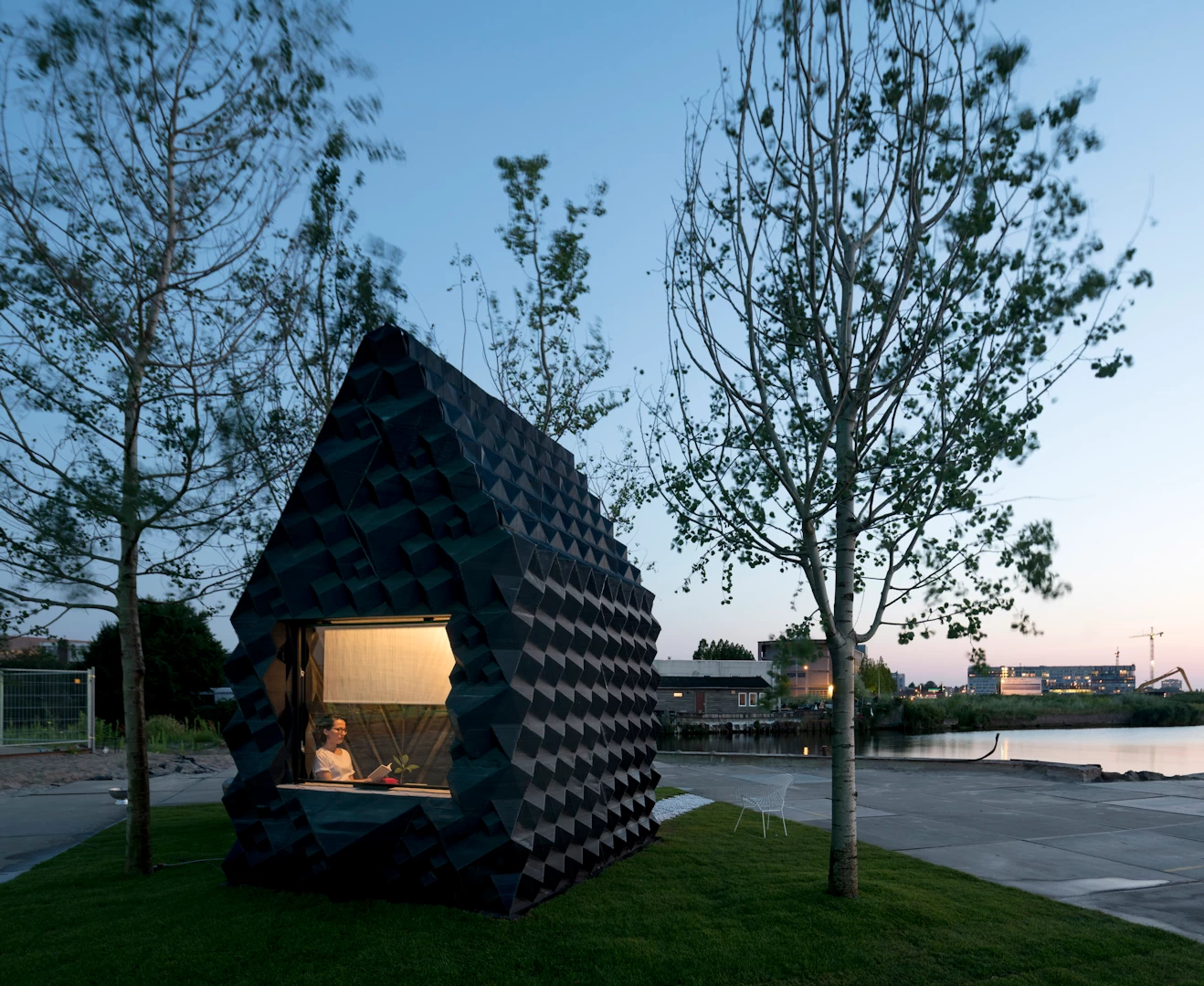 Front view of black 3d printed plastic cottage with textured walls on green lawn