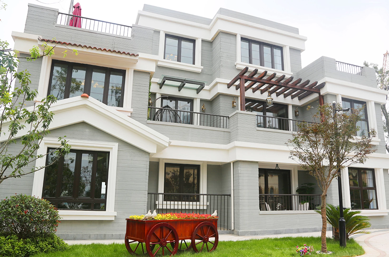 Front view of grey & white 3d printed triple storey concrete house with garden