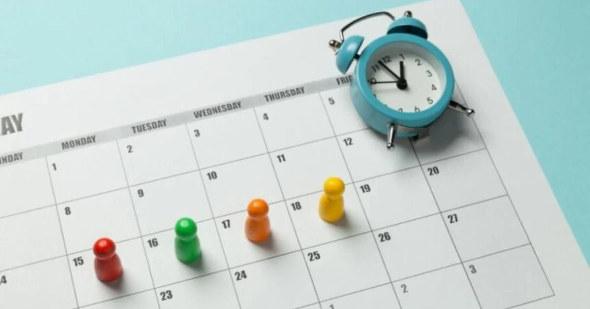 Quatro pinos de jogo em cima de um calendário, em dias diferentes. No canto superior direito do calendário, um relógio despertador de corda. A ideia é representar a semana de quatro dias de trabalho e o tempo ganho.